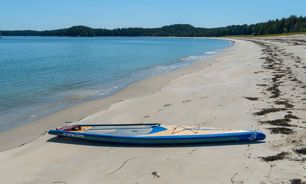 A photo of a paddleboard on a long, sandy beach.